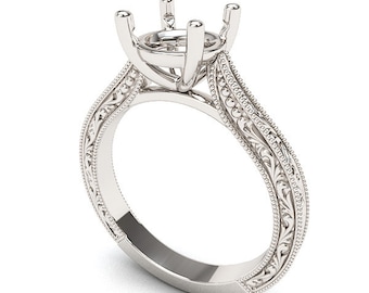 Op de afbeelding: Een zilverkleurige verlovingsring met een sierlijk ontwerp. De ring heeft een centrale zetting voor een edelsteen, omringd door gedetailleerd filigraan en parelranden. De band heeft een decoratief patroon.