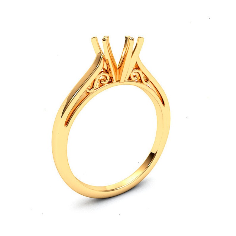 May include: A gold ring setting with a delicate, ornate design. The setting is designed to hold a center stone, with prongs to secure it in place.