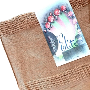 Peut inclure: Gros plan sur une paire de bas couleur sable avec une étiquette indiquant "Elite" Hosiery Made in England. L'étiquette présente un motif de roses et un fond vert.