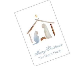May include: A watercolour Christmas card featuring a simple illustration of a nativity scene. The card is white with blue and brown watercolour paint. The text "Merry Christmas" and "The Harris Family" is printed in blue.