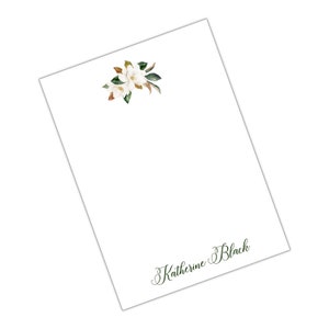 Könnte beinhalten: Weißer Notizblock mit einem floralen Design in der oberen Ecke und dem Namen "Katherine Black" in Kursivschrift unten.