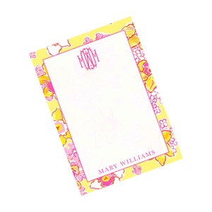Könnte beinhalten: Ein personalisierter Notizblock mit floralem Design. Der Notizblock hat einen gelben Hintergrund mit rosa und orangefarbenen Blumen. Die Mitte hat einen weißen Bereich mit den Initialen "MWM" und dem Namen "MARY WILLIAMS" in Pink.