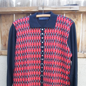 May include: Black and red argyle patterned cardigan with a button front closure. The cardigan has a collar and long sleeves. The label reads "Karen Scott".