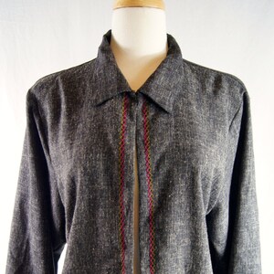 May include: A gray embroidered jacket with a pink and green floral design. The jacket has a long sleeve and a collar.
