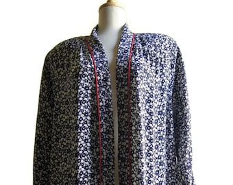 May include: A long, navy blue and white floral print robe with red trim along the edges. The robe has a shawl collar and two pockets.