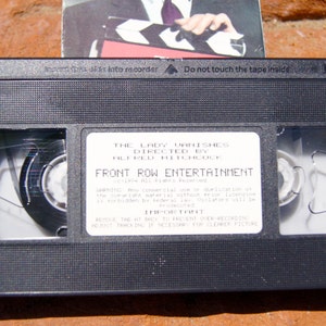 May include: A black VHS tape with a white label that reads "The Lady Vanishes Directed by Alfred Hitchcock Front Row Entertainment". The label also includes a warning about unauthorized duplication and instructions on how to prevent derecording.