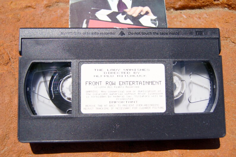 May include: A black VHS tape with a white label that reads "The Lady Vanishes Directed by Alfred Hitchcock Front Row Entertainment". The label also includes a warning about unauthorized duplication and instructions on how to prevent derecording.
