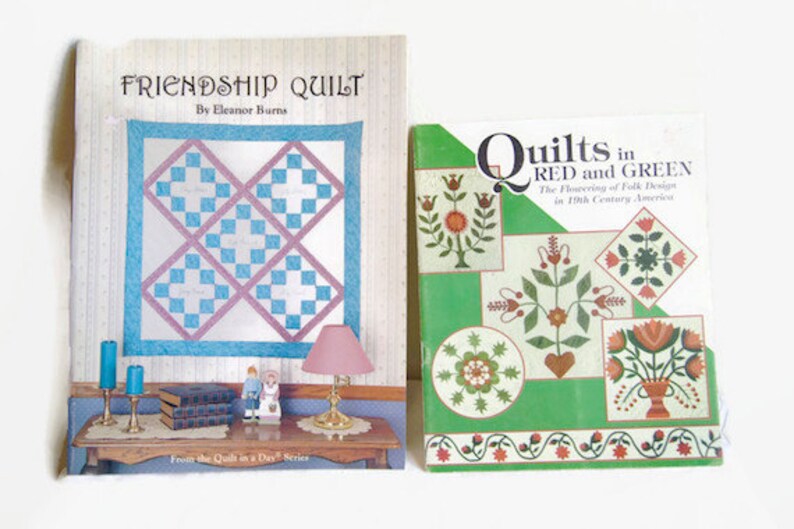 K&ouml;nnte beinhalten: Zwei Quiltb&uuml;cher, eines mit dem Titel "Friendship Quilt" von Eleanor Burns und das andere mit dem Titel "Quilts in Red and Green: The Flowering of Folk Design in 19th Century America".