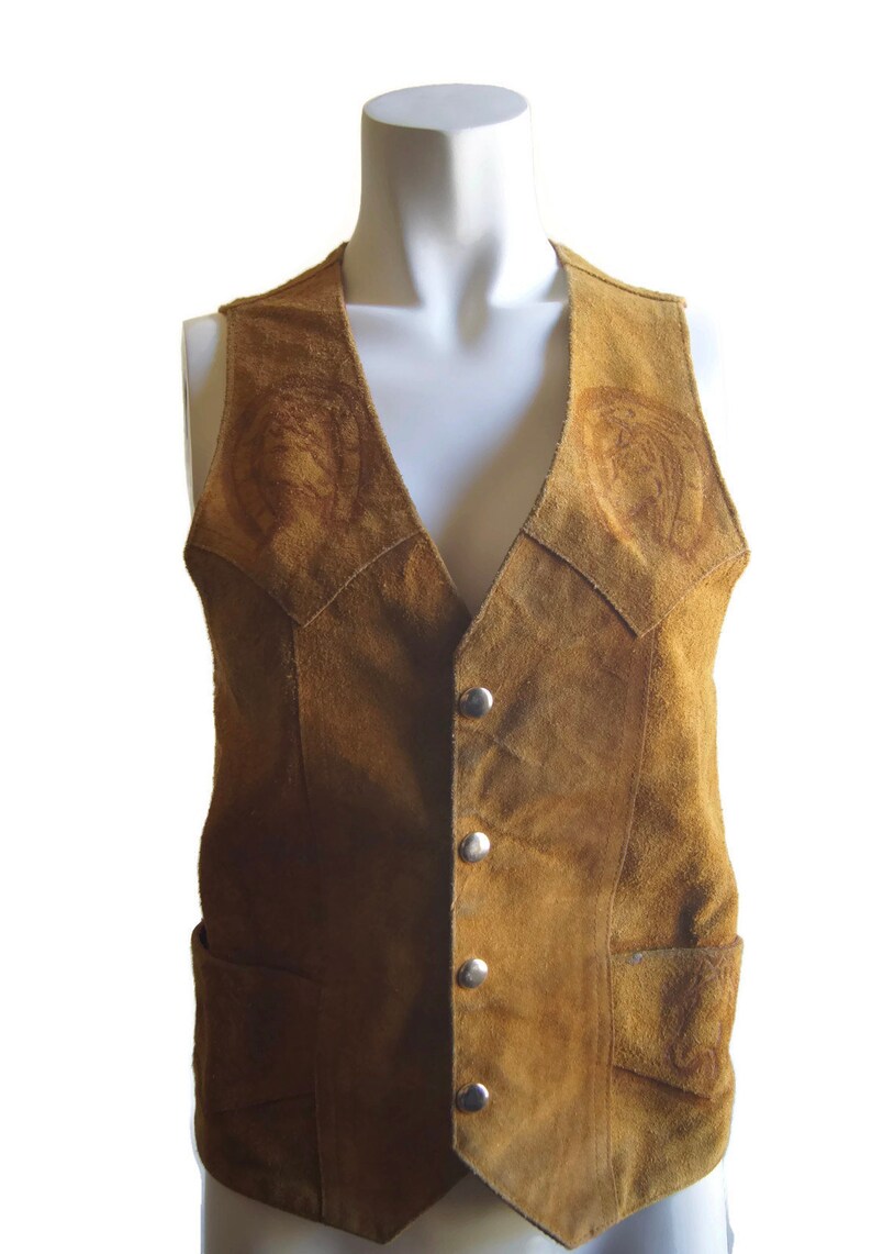 May include: A brown suede waistcoat with a V-neck and button fastening. The waistcoat has two pockets and decorative stitching on the front.