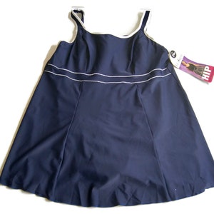 May include: Navy blue swimsuit with white trim. The swimsuit has a scoop neck and a skirt-like bottom. The tag reads "Hip, The Swimsuit Specialists."