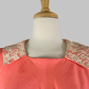 May include: A sleeveless coral dress with a white lace collar.