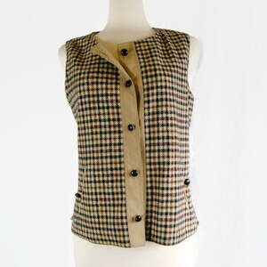 May include: A sleeveless vest with a brown and black plaid pattern. The vest has a button-up front and a brown fabric lining.
