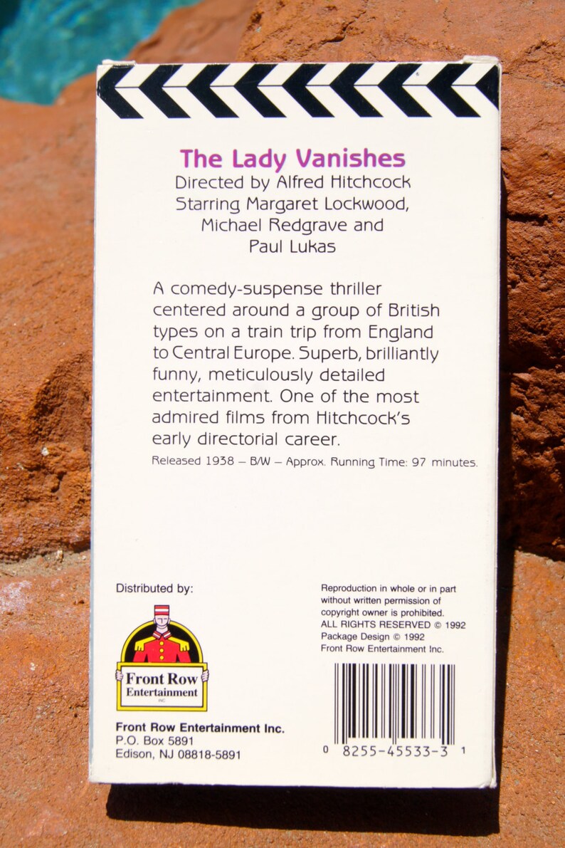 May include: The Lady Vanishes VHS tape case, featuring a black and white image of a clapperboard with arrows. The text on the case reads "The Lady Vanishes", "Directed by Alfred Hitchcock", "Starring Margaret Lockwood, Michael Redgrave and Paul Lukas", "Released 1938 - B/W - Approx. Running Time: 97 minutes."