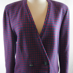 May include: A teal and pink houndstooth blazer with a single button closure and a v-neck.