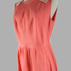 May include: A sleeveless coral pink dress with a white lace collar. The dress has a fitted bodice and a full skirt.
