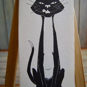 Op de afbeelding: Een zwart-witte felicitatiekaart met een cartoon zwarte kat met lange benen en de tekst "Happy Birthday".