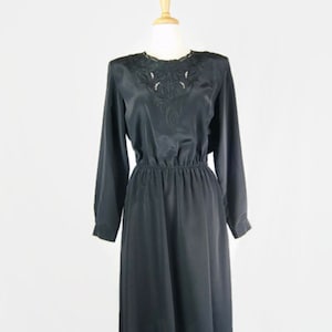 May include: A black midi dress with long sleeves and a lace neckline. The dress has a fitted bodice and a flowing skirt.