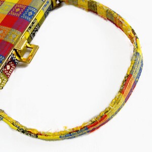 Puede incluir: Un bolso vintage con un dise&ntilde;o de patchwork colorido. El bolso presenta un cierre y accesorios de asa dorados. El asa tiene un patr&oacute;n de patchwork a juego. El cuerpo del bolso es una mezcla de cuadrados rojos, amarillos, azules y verdes.