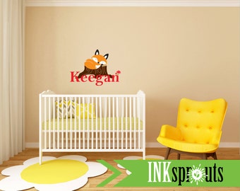 Könnte beinhalten: Ein weißes Babybett mit einer gelben und grauen gemusterten Decke und einem gelben Stuhl in einem Kinderzimmer mit einem Fuchs und dem Namen Keegan an der Wand.