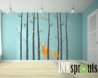 Könnte beinhalten: Ein Wandaufkleber mit der Silhouette eines Waldes mit Bäumen, Vögeln und Hirschen. Der Aufkleber ist in Grautönen und Orange gehalten und eignet sich perfekt für ein Kinderzimmer oder ein Babyzimmer.