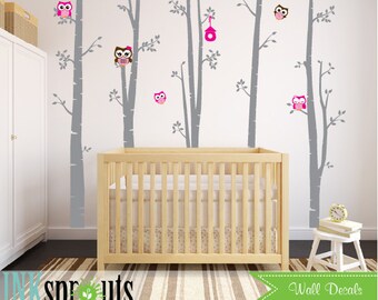 Könnte beinhalten: Graue Birkenbaum-Wandaufkleber mit rosa Eulen und einem Vogelhaus. Die Aufkleber befinden sich an einer weißen Wand in einem Kinderzimmer mit einem Kinderbett und einem weißen Hocker.