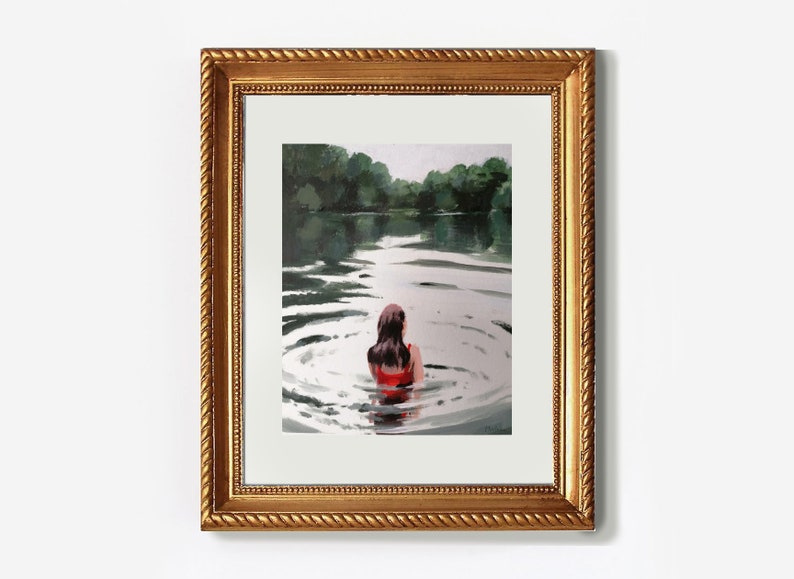 May include: A framed painting of a woman in a red swimsuit swimming in a lake. The water is calm and the woman is looking out at the trees on the other side of the lake.