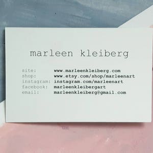 Op de afbeelding: Een witte visitekaartje met zwarte tekst. De kaart leest "marleen kleiberg" en bevat contactgegevens voor een website, winkel, Instagram, Facebook en e-mail.