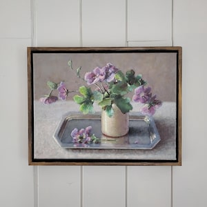 May include: A painting of a bouquet of purple flowers in a white vase on a silver tray. The flowers are arranged in a simple, elegant way, and the painting is done in a realistic style.
