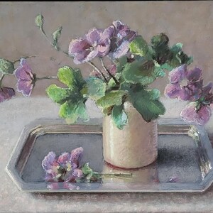May include: A bouquet of pale pink flowers in a cream-colored vase, sitting on a silver tray. The flowers are arranged in a loose, natural style, and the vase is simple and elegant.