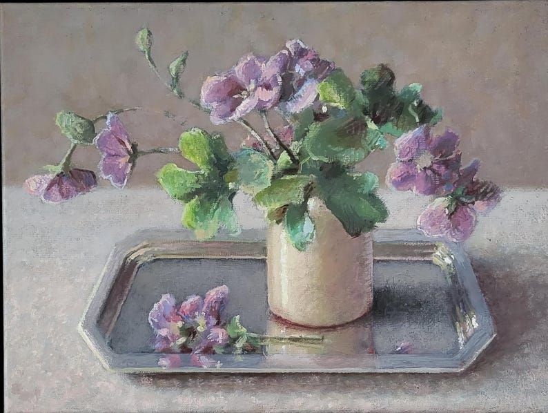 May include: A bouquet of pale pink flowers in a cream-colored vase, sitting on a silver tray. The flowers are arranged in a loose, natural style, and the vase is simple and elegant.