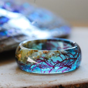 Blue ocean resin ring made of real red seaweed, beach sand and little seashells. The band is 8 mm wide.