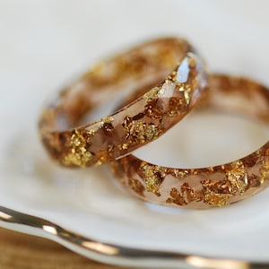 May include: Two gold resin rings with embedded gold flakes. The rings are stacked on top of each other.