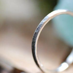 Puede incluir: Un anillo de banda martillado de plata con un acabado liso y pulido.