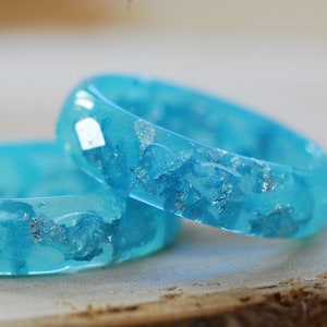 Resin ring faceted and geometric on the outside made of pastel blue color and silver flakes