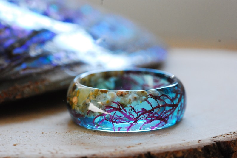Blue ocean resin ring made of real red seaweed, beach sand and little seashells. The band is 8 mm wide.