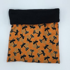 Puede incluir: Bolsa de tela naranja con forro de vellón negro y estampado de gato negro.