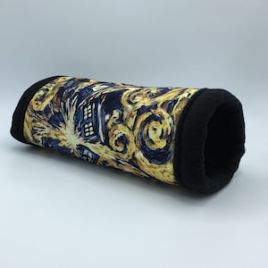 May include: A pet tunnel with a design inspired by Van Gogh's "Starry Night" and a blue police box. The fabric features swirling yellow and blue patterns. The ends and interior are lined with black fabric, creating a comfortable space for small animals.