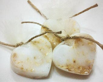May include: Three heart-shaped soaps with a white base and gold flecks, wrapped in sheer white netting and tied with twine.
