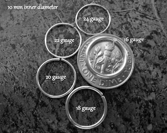 May include: A set of six silver hoop earrings in different sizes, ranging from 16 gauge to 24 gauge. The earrings are displayed on a gray surface with a US dime for size comparison. The text "10 mm inner diameter" is visible at the top of the image.