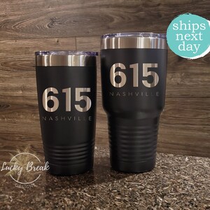 May include: Two black stainless steel tumblers with a silver inscription that reads "615 NASHVILLE".