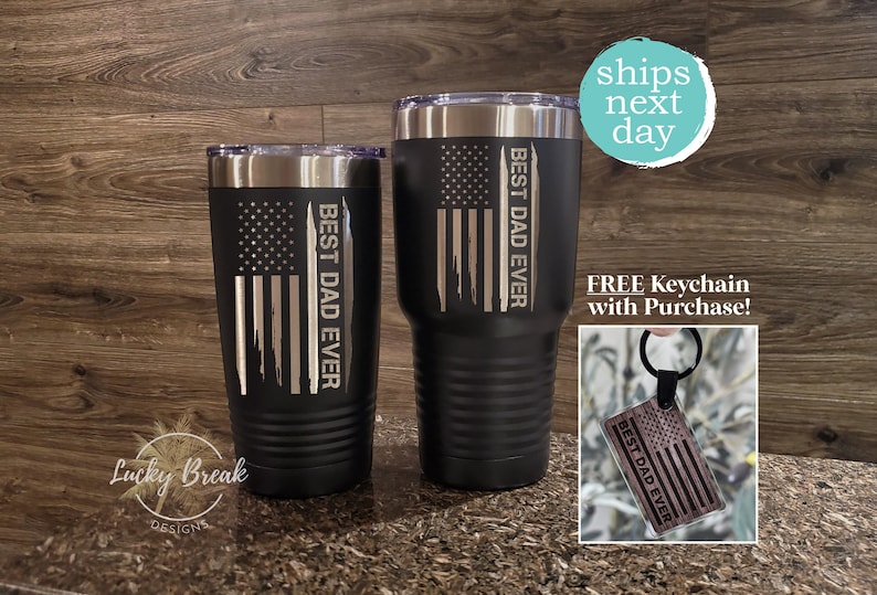 May include: Two black stainless steel tumblers with a white and grey American flag design and the text "Best Dad Ever". A matching wooden keychain with the same design is included.