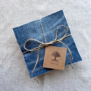 May include: Square denim fabric wrapped with twine and a brown tag. The tag features a tree illustration and the text "Uniquely Orchard". The denim has a blue wash and is tied with a natural twine bow.