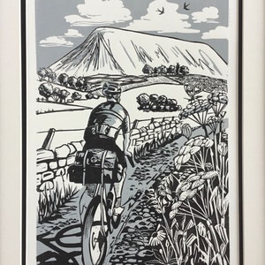May include: A black and white linocut print of a cyclist riding a bicycle up a hill. The cyclist is wearing a helmet and a backpack. The hill is in the background and there are trees and a stone wall in the foreground. The print is titled "Caerphilly Paradise" and signed by the artist.