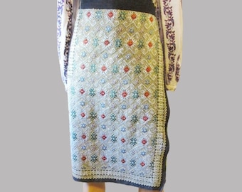 May include: A white skirt with a geometric pattern in shades of green, blue, and red. The skirt is made of a woven fabric and has a black waistband.