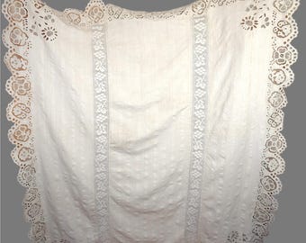 May include: A white lace tablecloth with a scalloped edge. The vintage-style cloth has vertical stripes and two central lace panels with floral and leaf patterns. The edges are decorated with intricate floral cutouts.