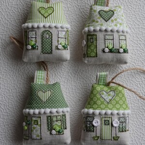 Può includere: Quattro ornamenti per la casa fatti a mano in tessuto verde e bianco con bottoni bianchi e un cuore sul tetto. Ogni casa ha un anello di corda per appendere.