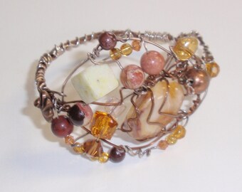 Mixed metals beaded cuff is Studded with agates and crystals, measures 2 inches wide at top, has a Side clasp and fits medium-large wrist.