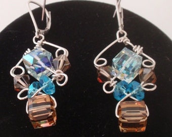 Swarovski crystals wrapped in sterling silver form sparkling chandelier earrings in shades of blue and gold tones on silver earwires.