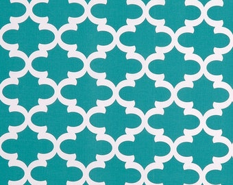 Op de afbeelding: Een turquoise en wit patroonstof. Het ontwerp heeft een herhalend patroon van witte vierpasvormen tegen een turquoise achtergrond. De stof heeft een getextureerde uitstraling, wat suggereert dat deze gebruikt kan worden voor bekleding of woondecoratie.