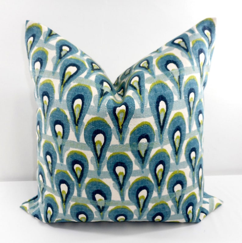 Pu&ograve; includere: Cuscino quadrato decorativo con un motivo a goccia turchese, blu navy e verde su sfondo bianco. Il cuscino ha un aspetto morbido e strutturato. Il design &egrave; ripetuto su tutta la superficie del cuscino.